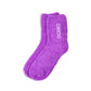 A pair of fluffy purple socks with DOMO embroidered in white. Set against a white background. 